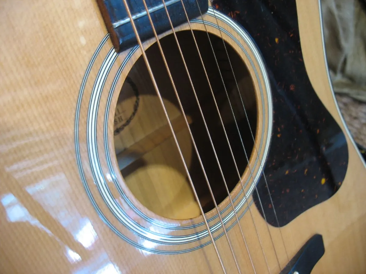 Boca y cuerdas de una guitarra acústica de cuerdas de acero