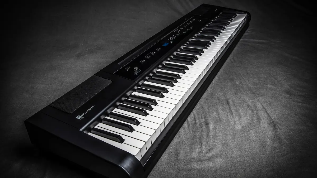 Piano digital portátil de 88 teclas con mecánica de martillos, fotografiado en estudio sobre fondo oscuro